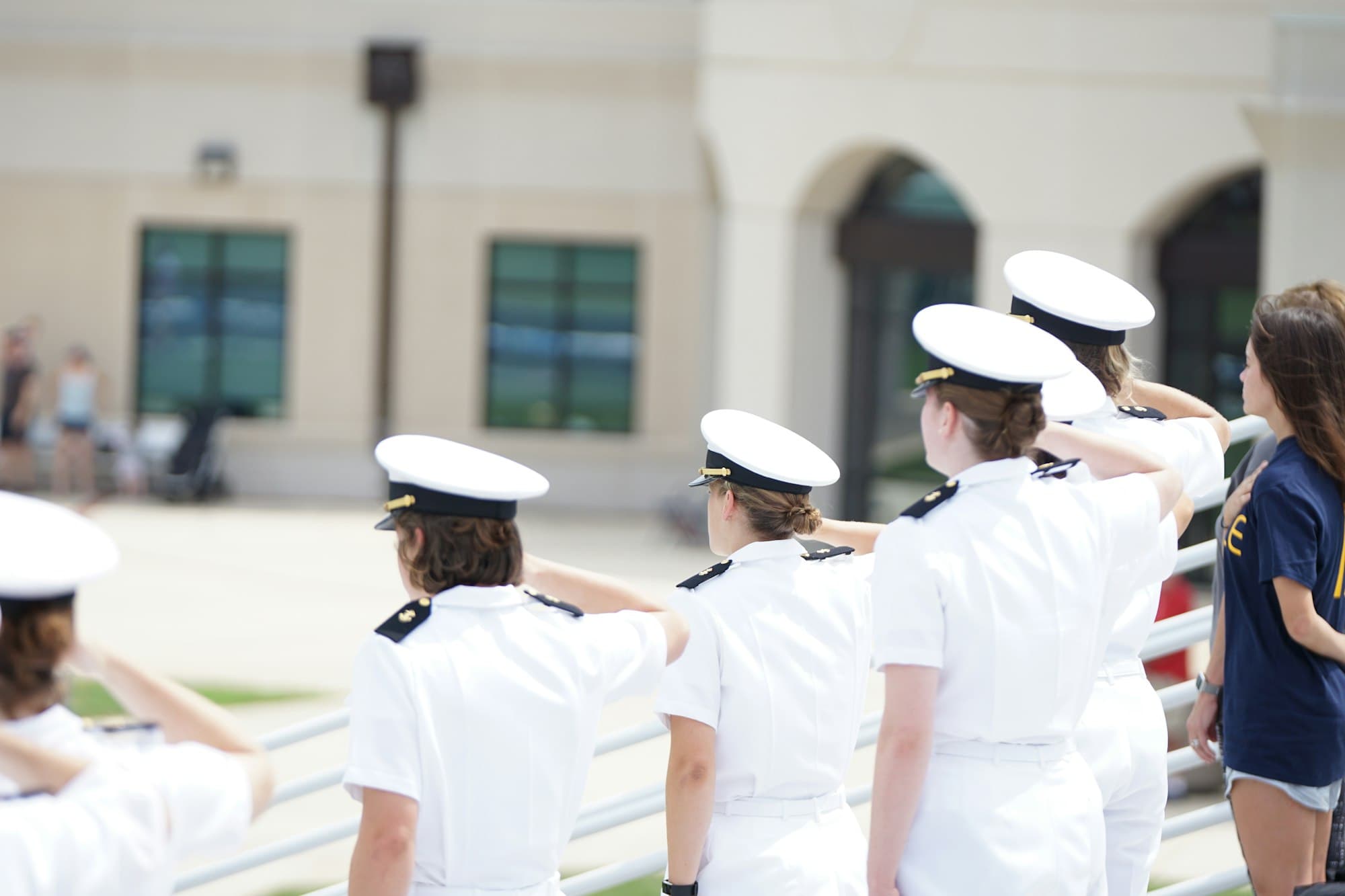 Service academy midshipmen saluting during a ceremony